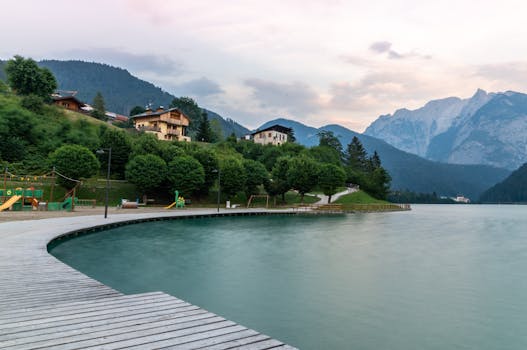 Picturesque view of a serene lake surrounded by mountains and lush greenery in Veneto, Italy at dusk.