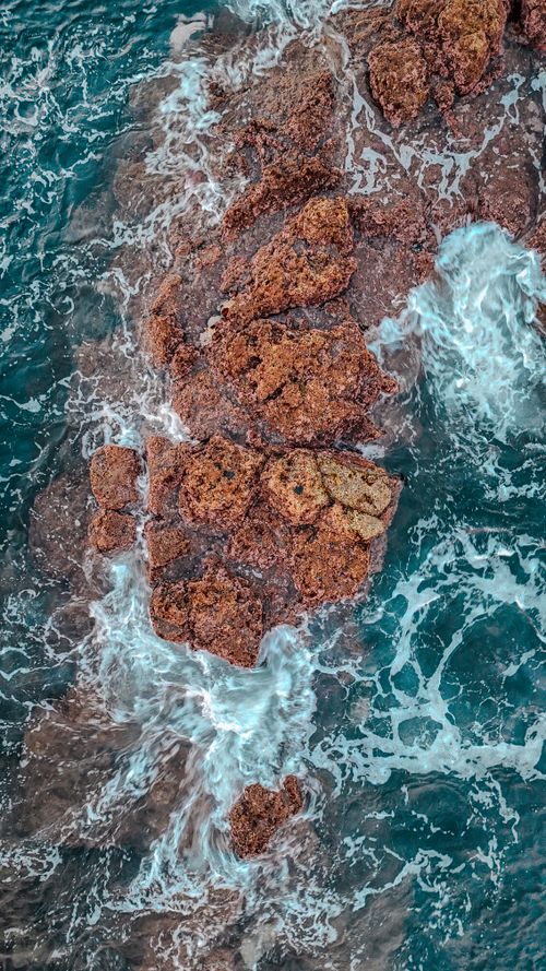 Free Stunning aerial view of the rugged Azores coastline with waves crashing against rocks. Stock Photo