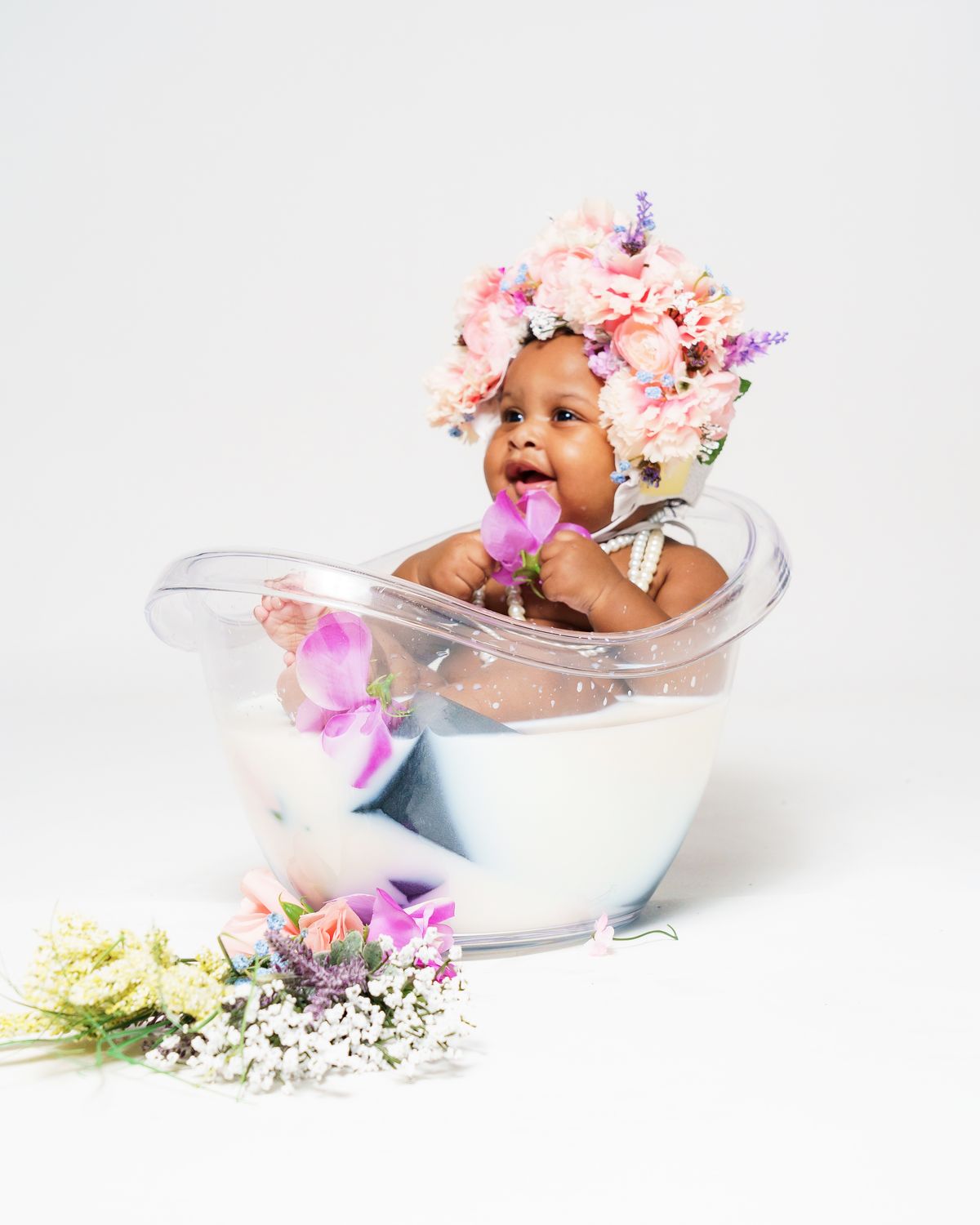 Baby in a milk bath with a floral crown for first birthday photoshoot ideas