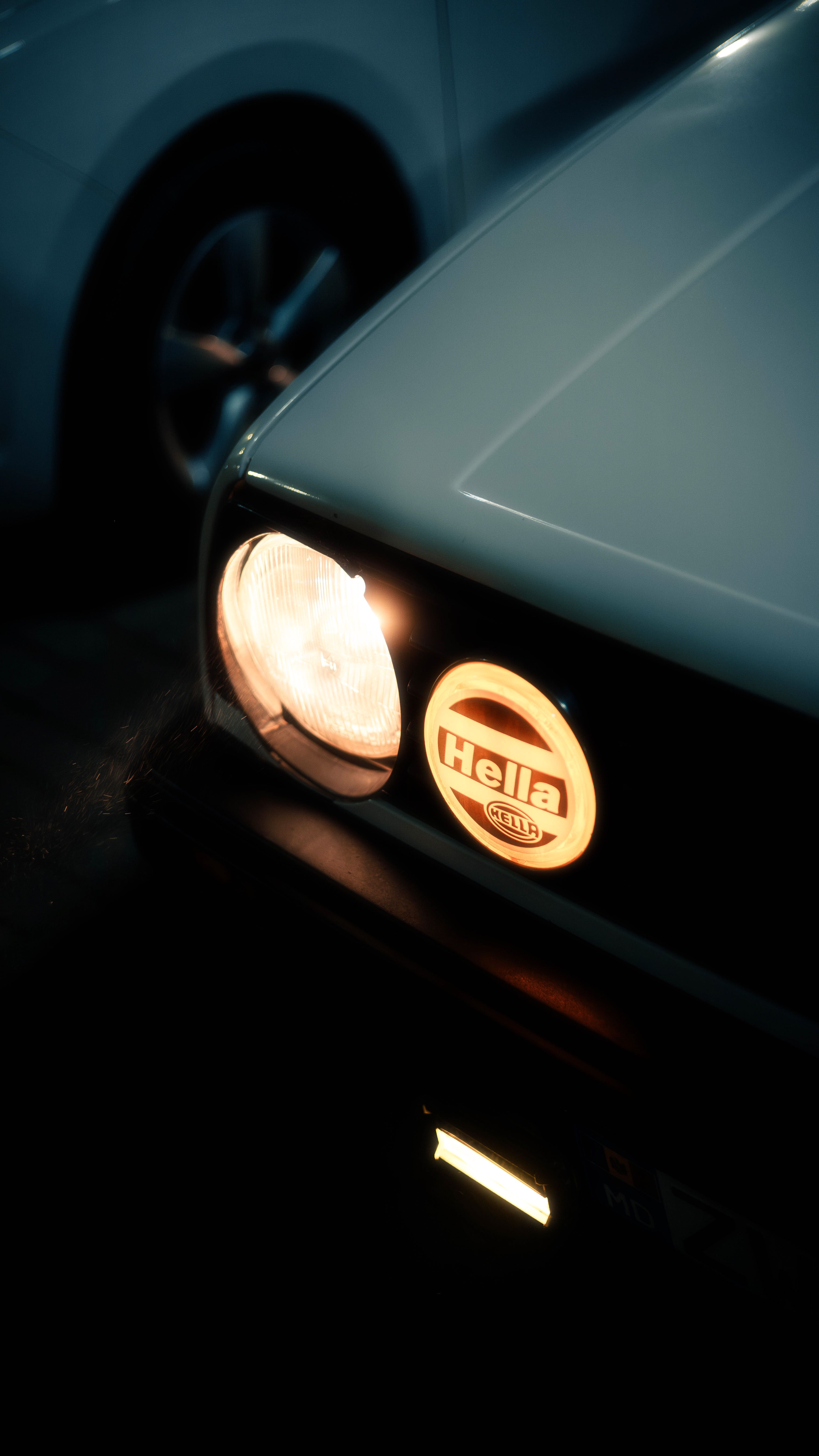 Close-up of a vintage car's headlights glowing at night, showcasing classic style.