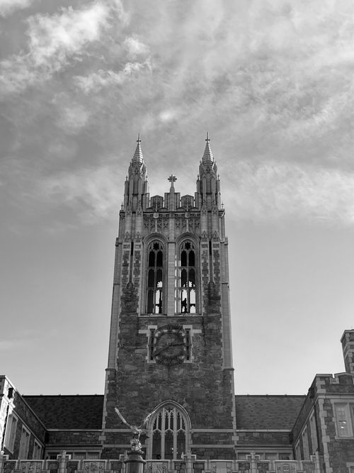 Free Gothic-style tower reaching into a cloudy sky, emphasizing historic architecture. Stock Photo