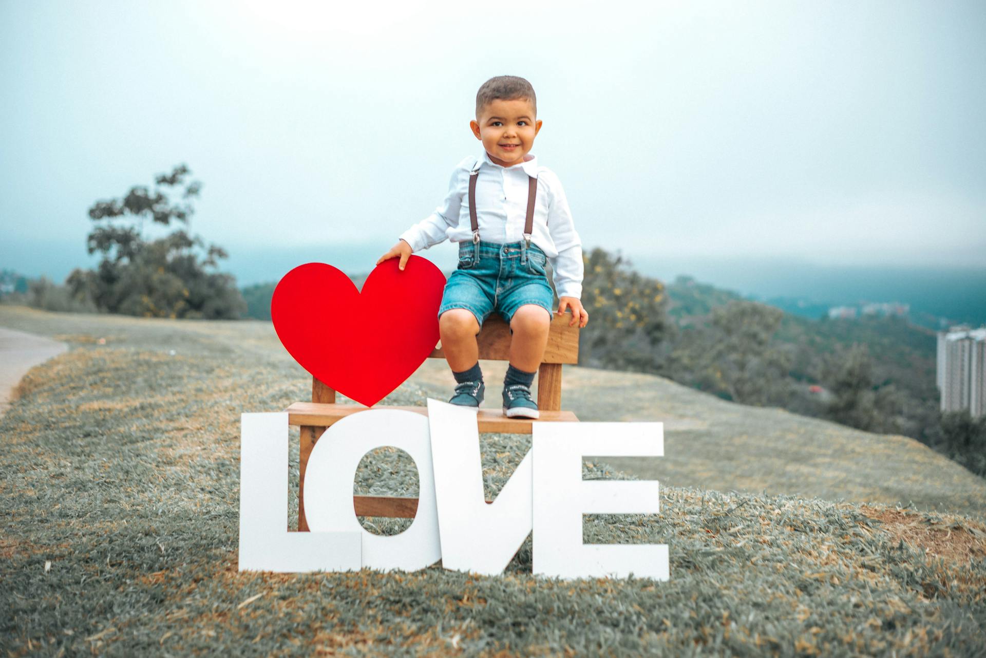 Adorable child sitting with a love sign outdoors in Caracas park, Venezuela.