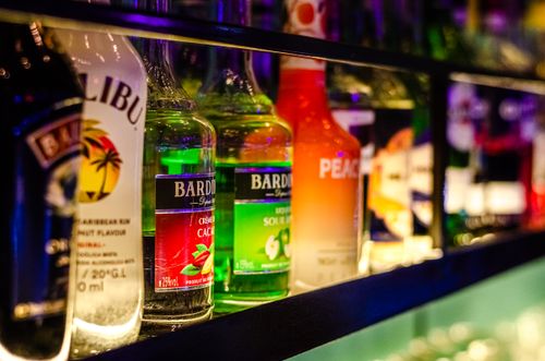 Free Vibrant array of liquor bottles displayed on a bar shelf, with vivid lighting. Stock Photo