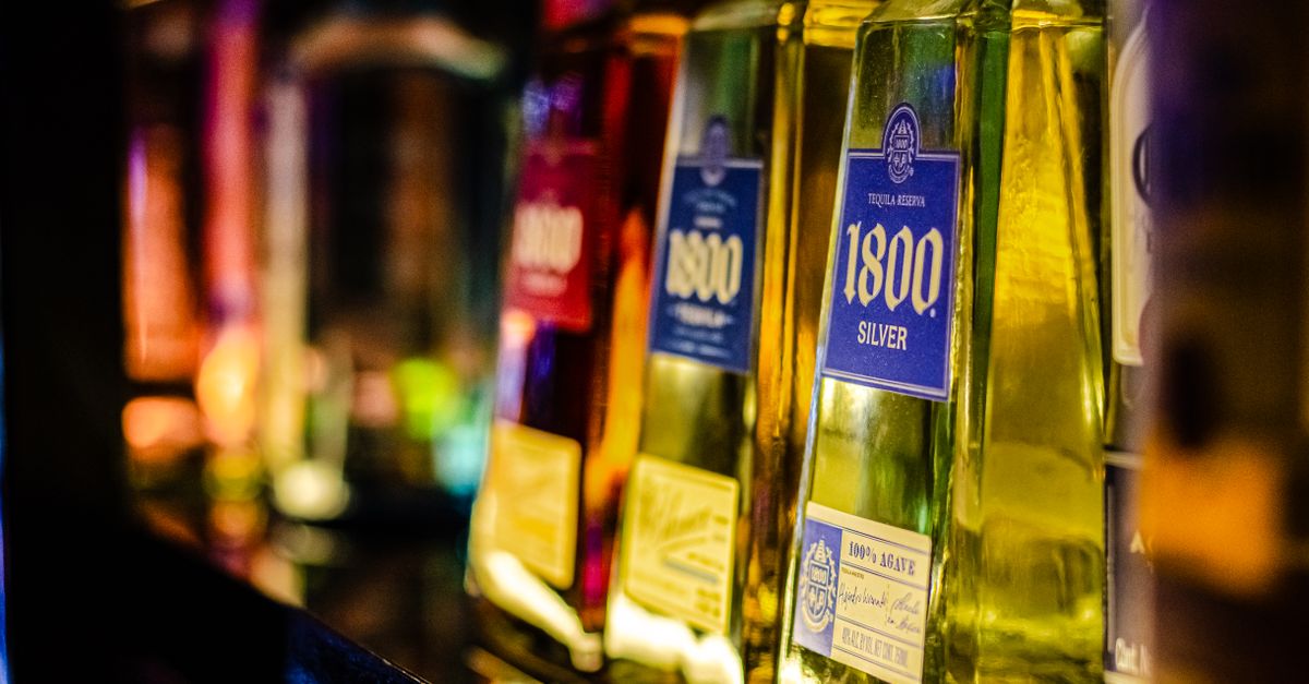 Colorful liquor bottles lined up on a bar shelf, highlighting tequila selection.