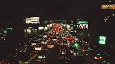 城市道路上交通繁忙，夜间灯火通明，周围建筑物明亮