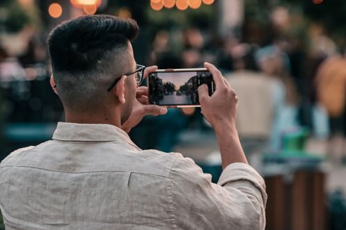 Free A man photographs a vibrant street scene in Montréal using his smartphone. Stock Photo
