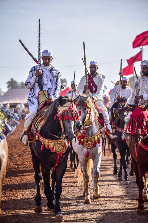 Free Moroccan horsemen in traditional attire parade at Ain El Aouda festival, showcasing cultural heritage. Stock Photo