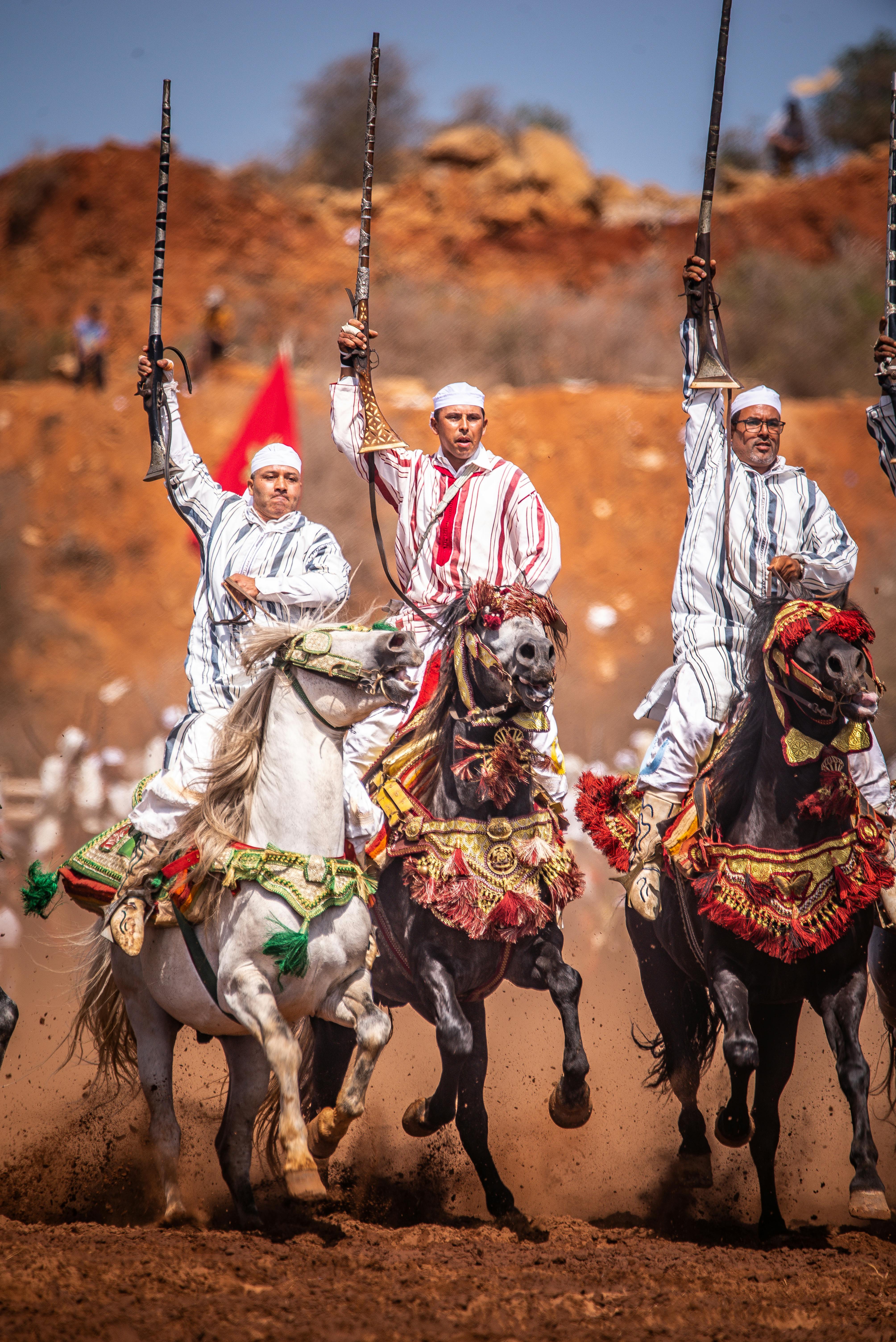 Men on decorated horses perform at a traditional Moroccan festival.