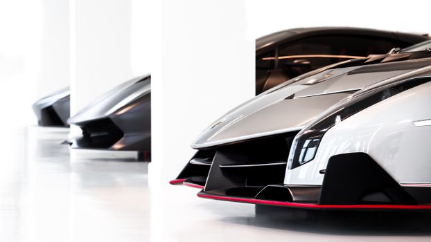 Close-up of luxury sports cars showcased in a sleek, modern museum setting.