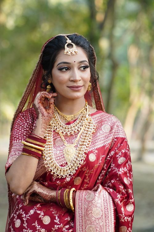 Free Beautiful Indian bride wearing red saree and gold jewelry outdoors. Stock Photo