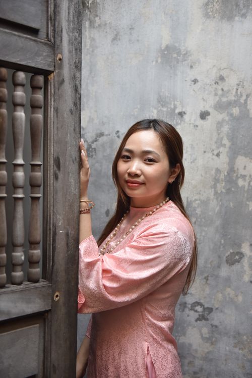 Free Portrait of a young woman in a pink traditional dress standing indoors. Stock Photo