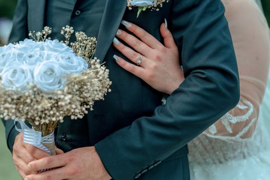 Close-up of a bride and groom embracing, showcasing a beautiful bouquet and ring.