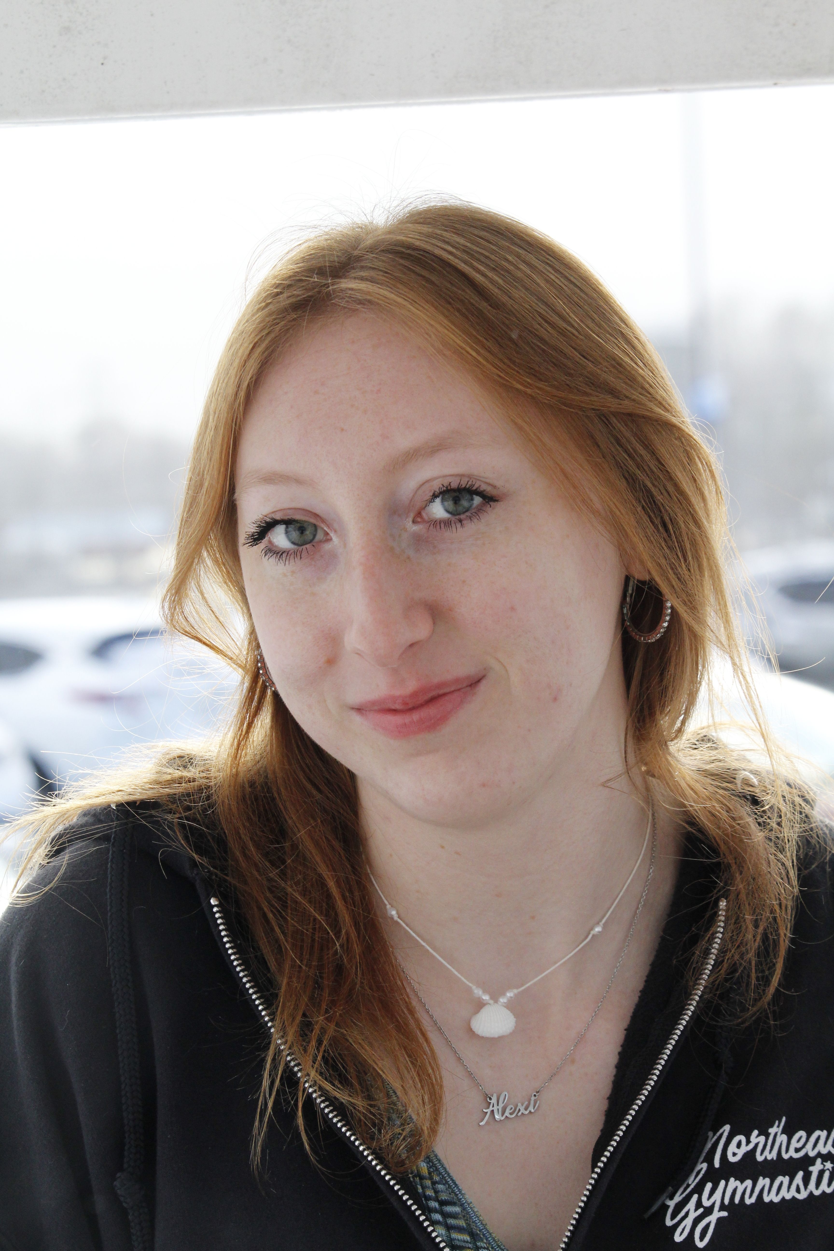 Outdoor portrait of a young woman with a warm smile on a bright day.