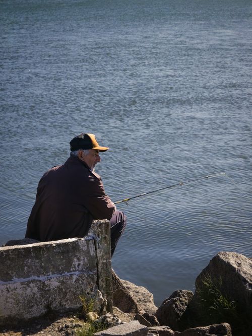 Free An elderly man fishing by a serene sea in Santa Catarina, Brazil, capturing peaceful coastal life. Stock Photo