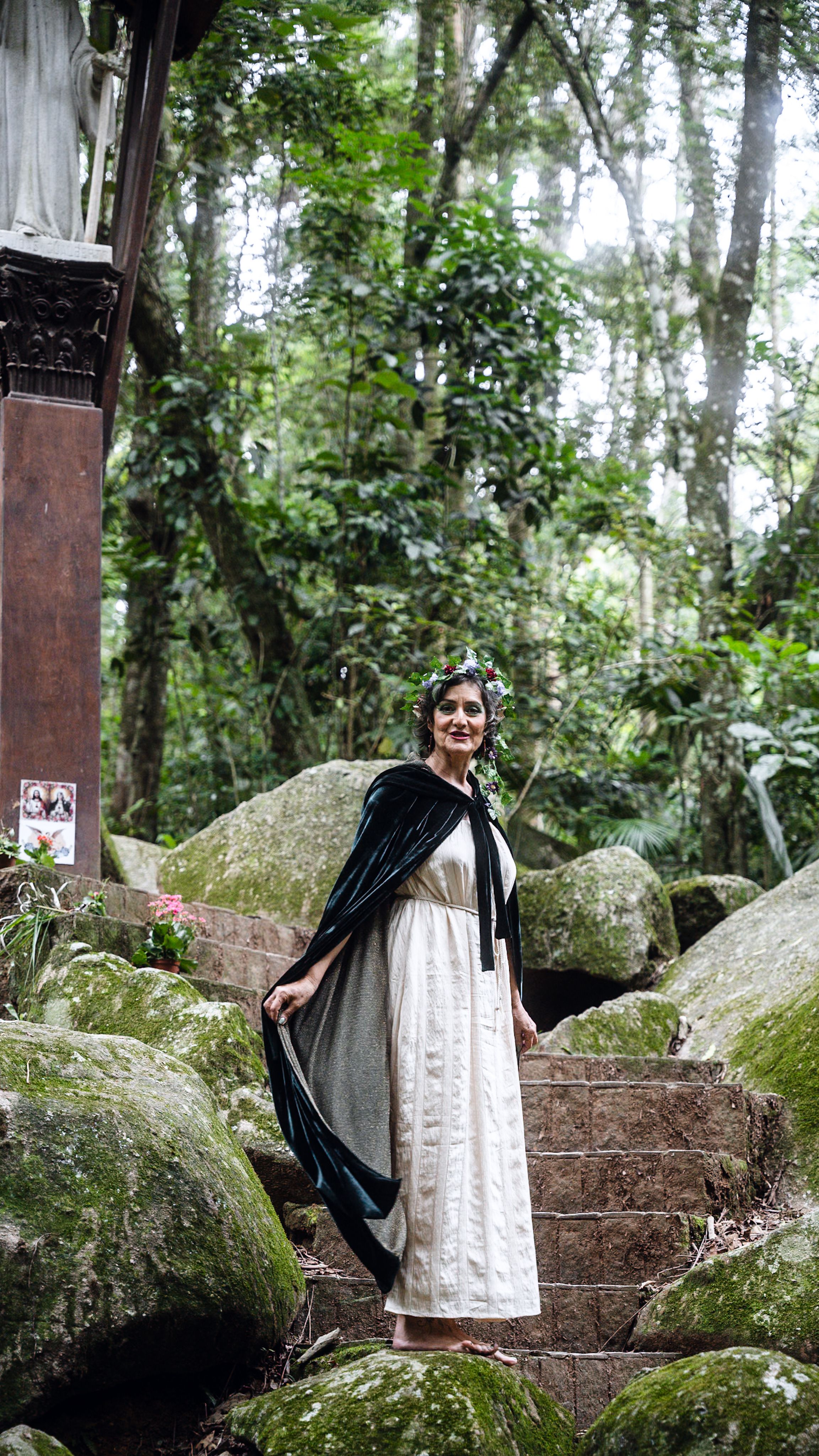 A woman in a vintage dress stands amidst a lush forest setting, exuding mystery and elegance.