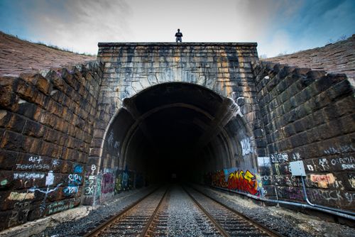 Free Person stands atop a graffiti-covered railway tunnel, capturing urban exploration and thrill. Stock Photo