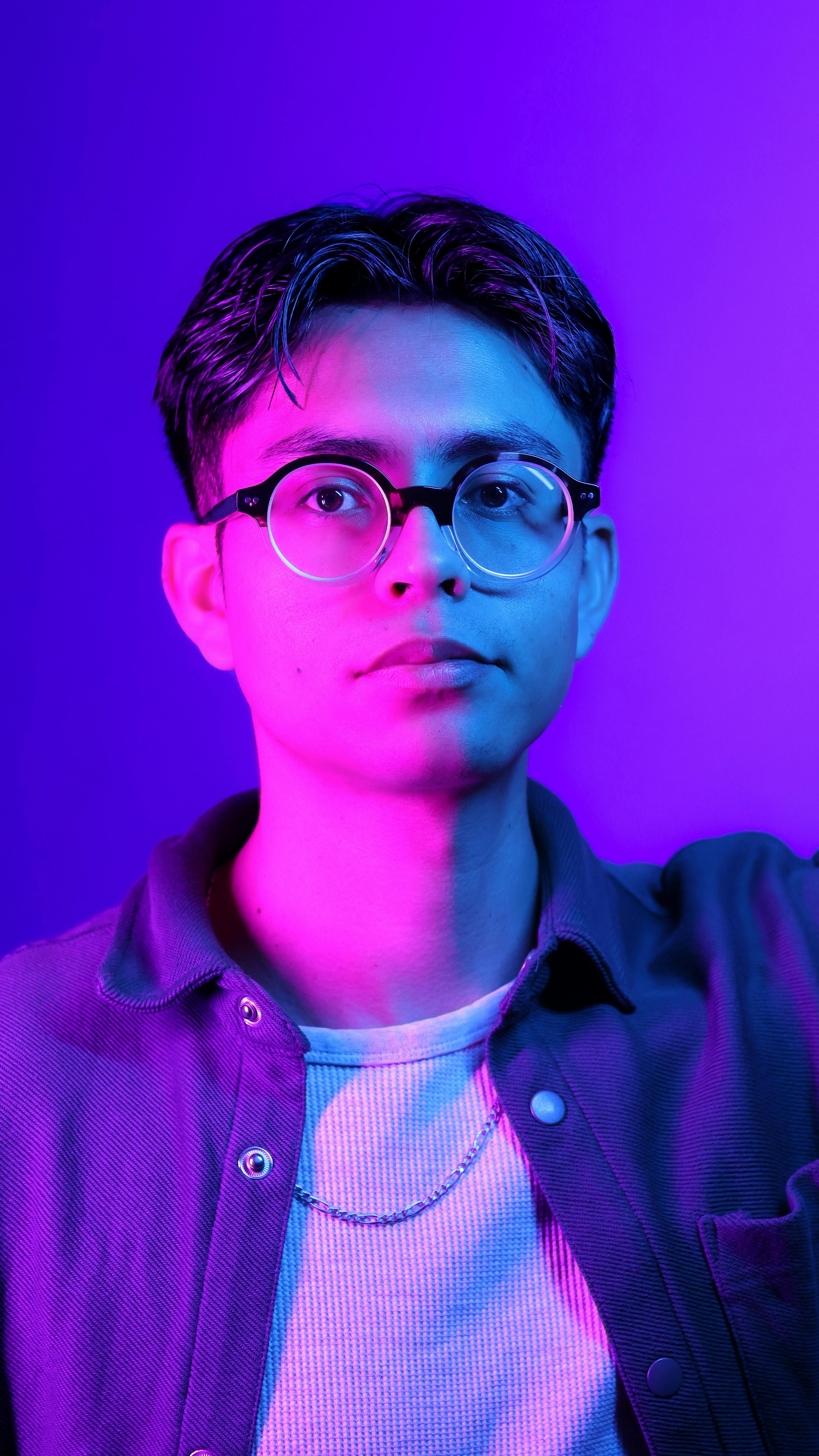 A striking neon portrait featuring a young man in glasses, highlighted by blue and purple lighting.