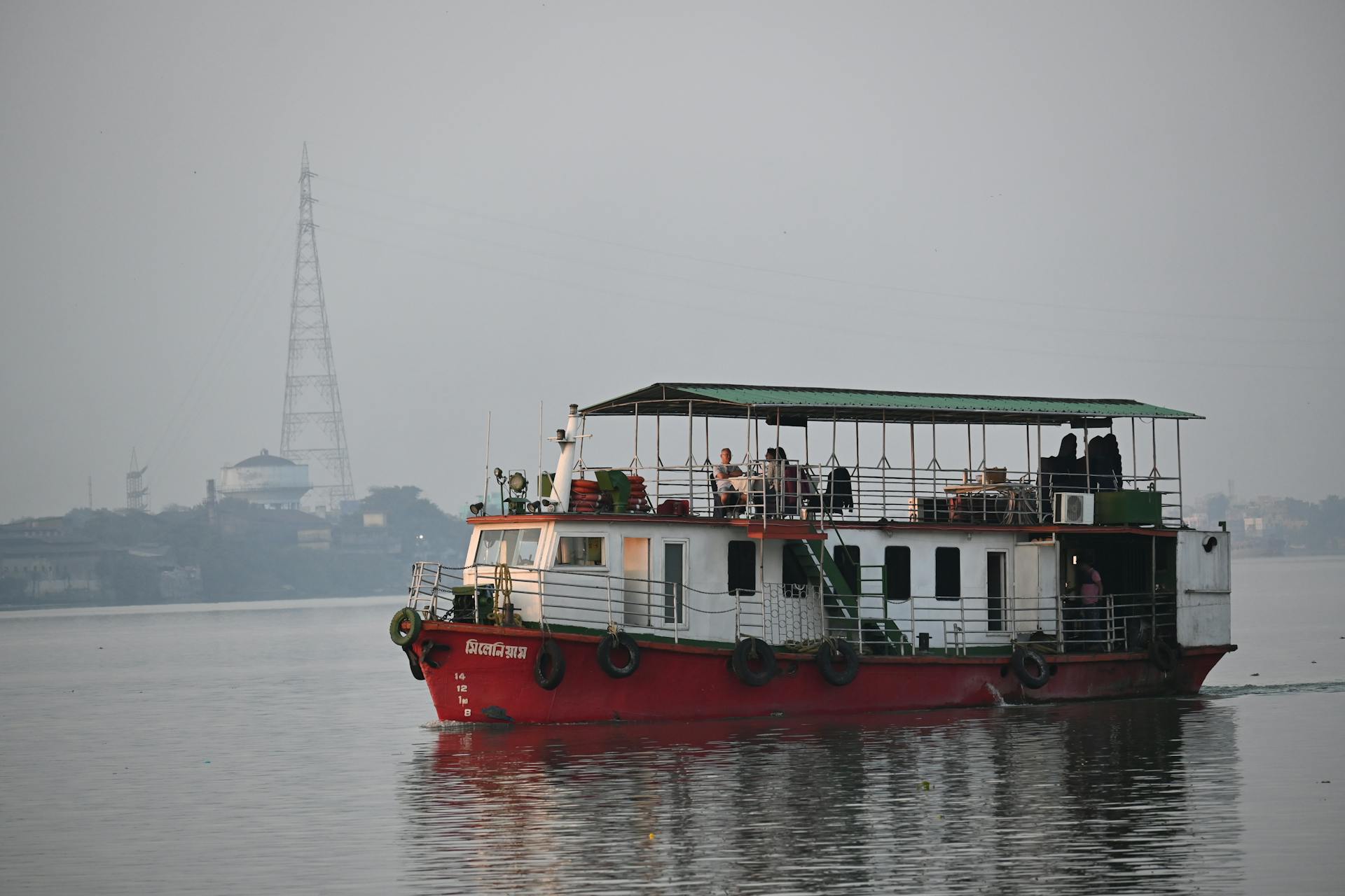 Passenger boat cruising on the Ganges River in Kolkata at sunset, with cityscape in the background.