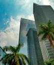 低角度拍摄的雅加达现代摩天大楼与棕榈树，映衬在充满活力的天空下
