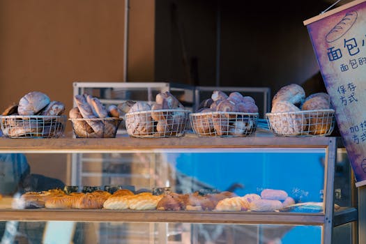 A variety of fresh bread loaves and rolls displayed in baskets at a bakery.