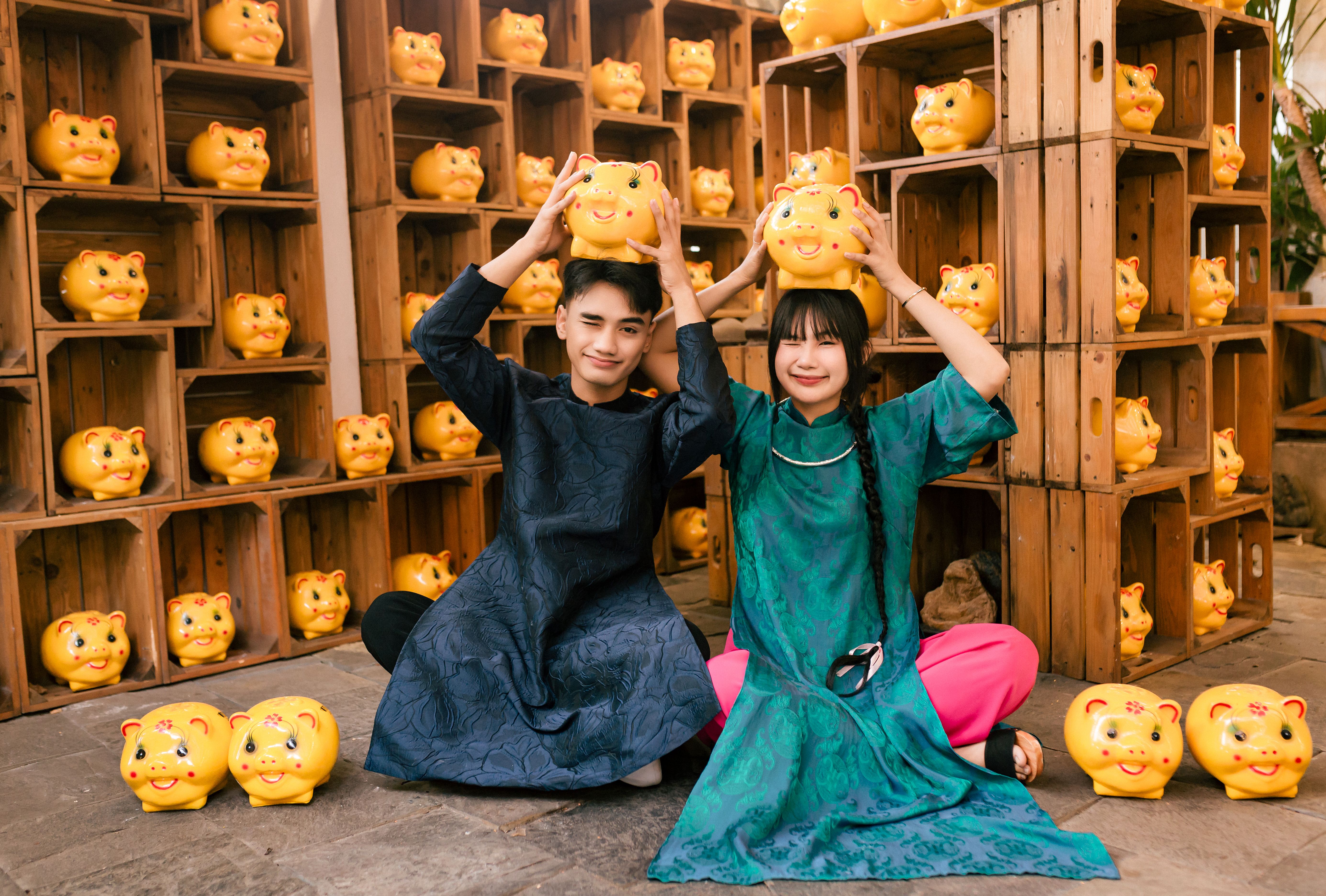 A joyful Vietnamese couple posing with traditional piggy banks in Hội An.