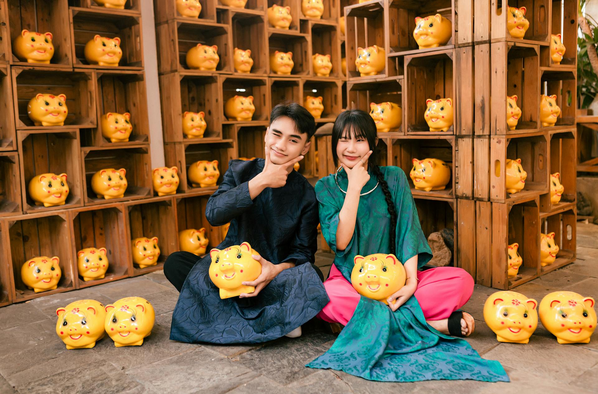 A couple in traditional costumes holding piggy banks in Hội An, Vietnam.