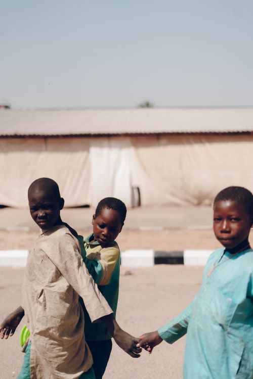 Free Three children walking hand in hand outdoors in sunny weather, expressing friendship and unity. Stock Photo