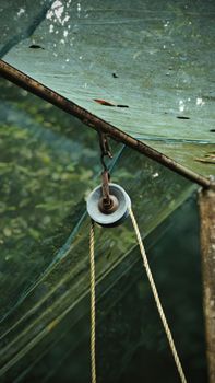 Close-up of a rustic pulley system under a weathered tarp in an outdoor environment.