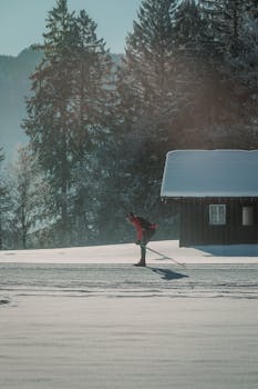 A cross-country skier gliding through a serene snowy forest with a rustic cabin in the background.