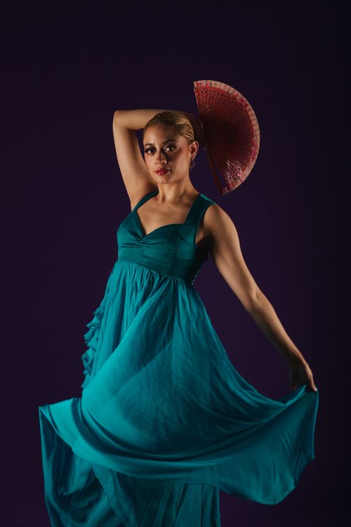 Free Woman in a teal dress elegantly posing with a red fan against a dark background. Stock Photo