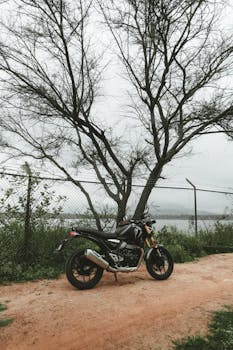 A black motorcycle parked by a serene lakeside in Bengaluru, India.