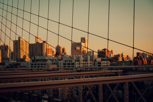 Sunset view of the Manhattan skyline from the Brooklyn Bridge, NYC. Urban architecture at dusk.