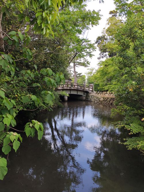 Free A peaceful bridge crossing a tranquil river surrounded by lush greenery in Matsusaka, Mie, Japan. Stock Photo