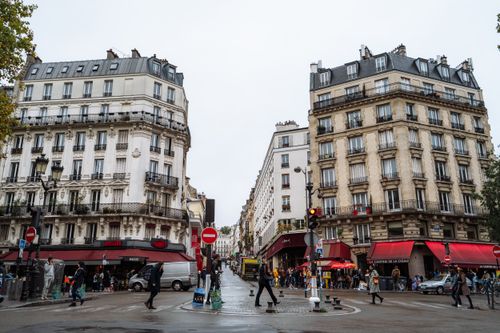 Free A quaint Parisian street captured on a rainy day, showcasing classic European architecture and vibrant café culture. Stock Photo