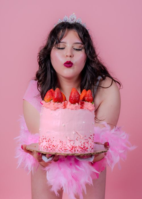 Free Woman celebrates birthday with pink cake and strawberries, exuding happiness and elegance. Stock Photo