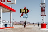 以沙漠为背景的明亮加油站和汽车旅馆，设有工作人员和充满活力的标牌