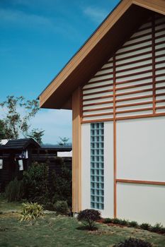 A minimalist house exterior with wooden accents and a garden in the foreground.