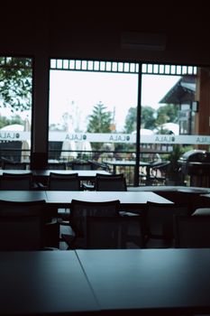 Empty restaurant with outdoor view showing trees and patio seating.