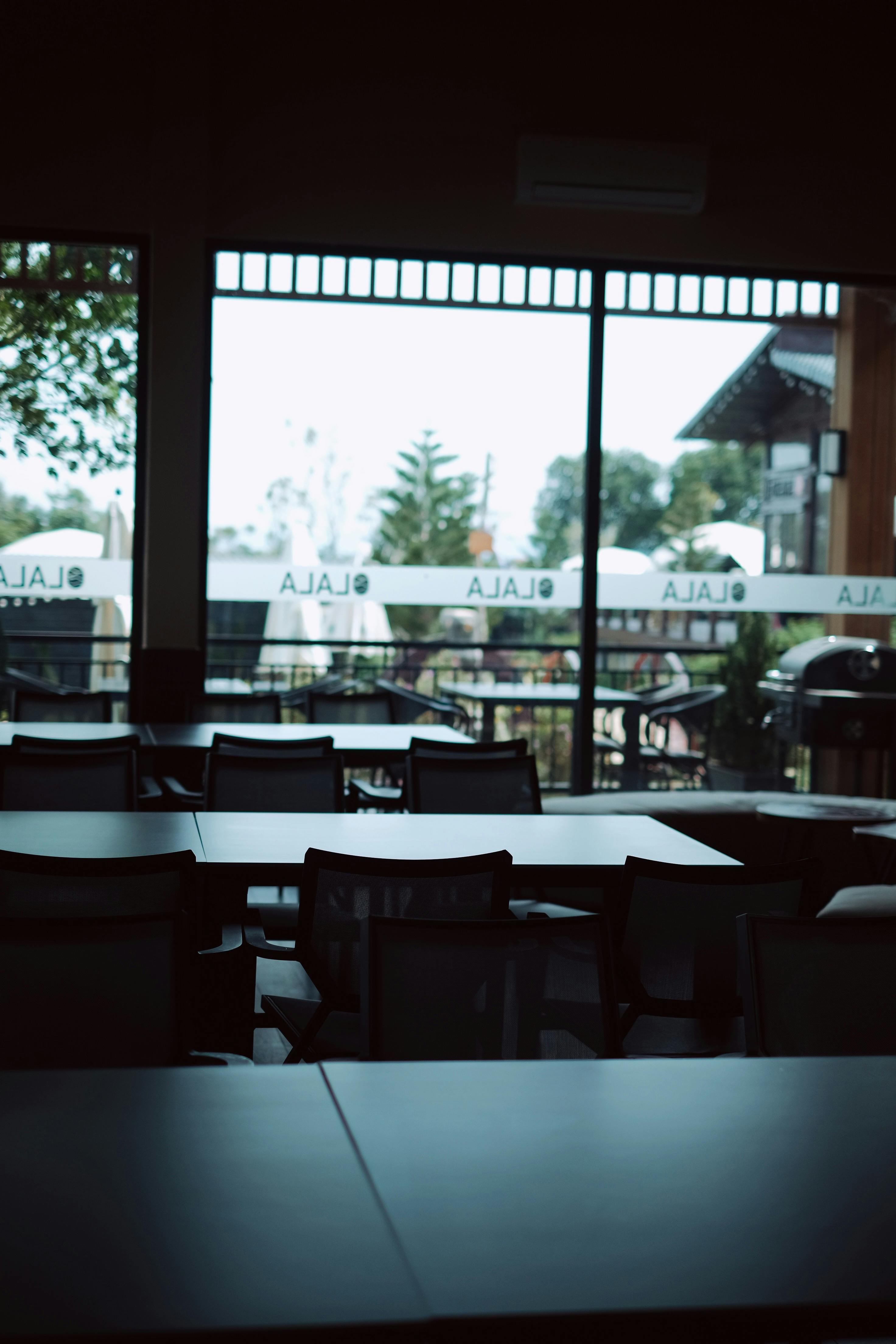 Kostenlos Leeres Restaurant mit Blick nach draußen auf Bäume und Sitzgelegenheiten auf der Terrasse. Stock-Foto