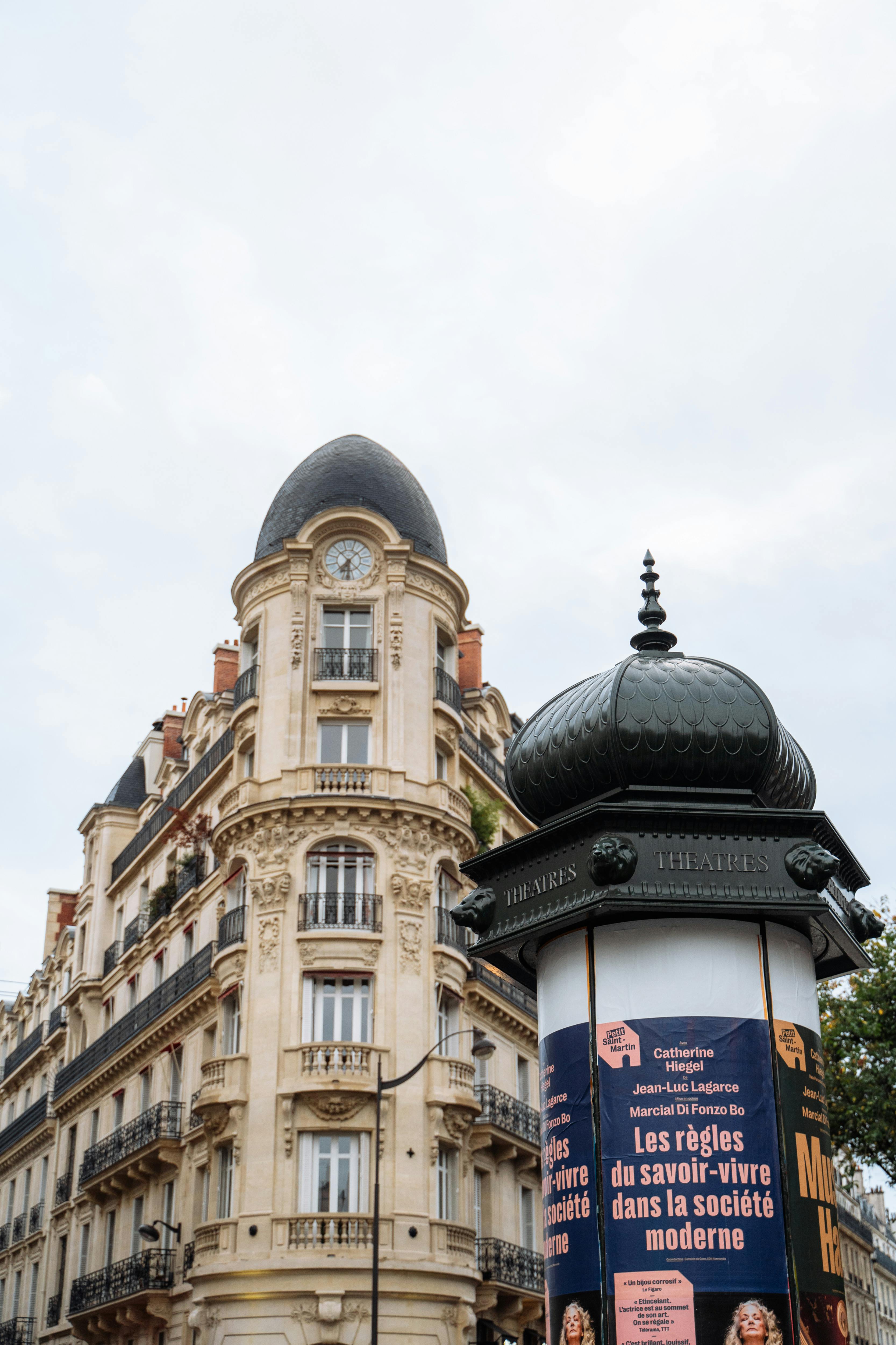Ücretsiz Paris'in kentsel kesiminde bir tiyatro büfesinin yanında süslü balkonlara sahip zarif bir Paris binası. Stok Fotoğraflar