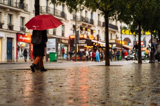 A vibrant Paris street scene with a red umbrella reflecting Parisian charm on a rainy evening.