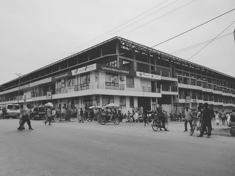 A black and white photo capturing a busy city street with a historic building in the background.