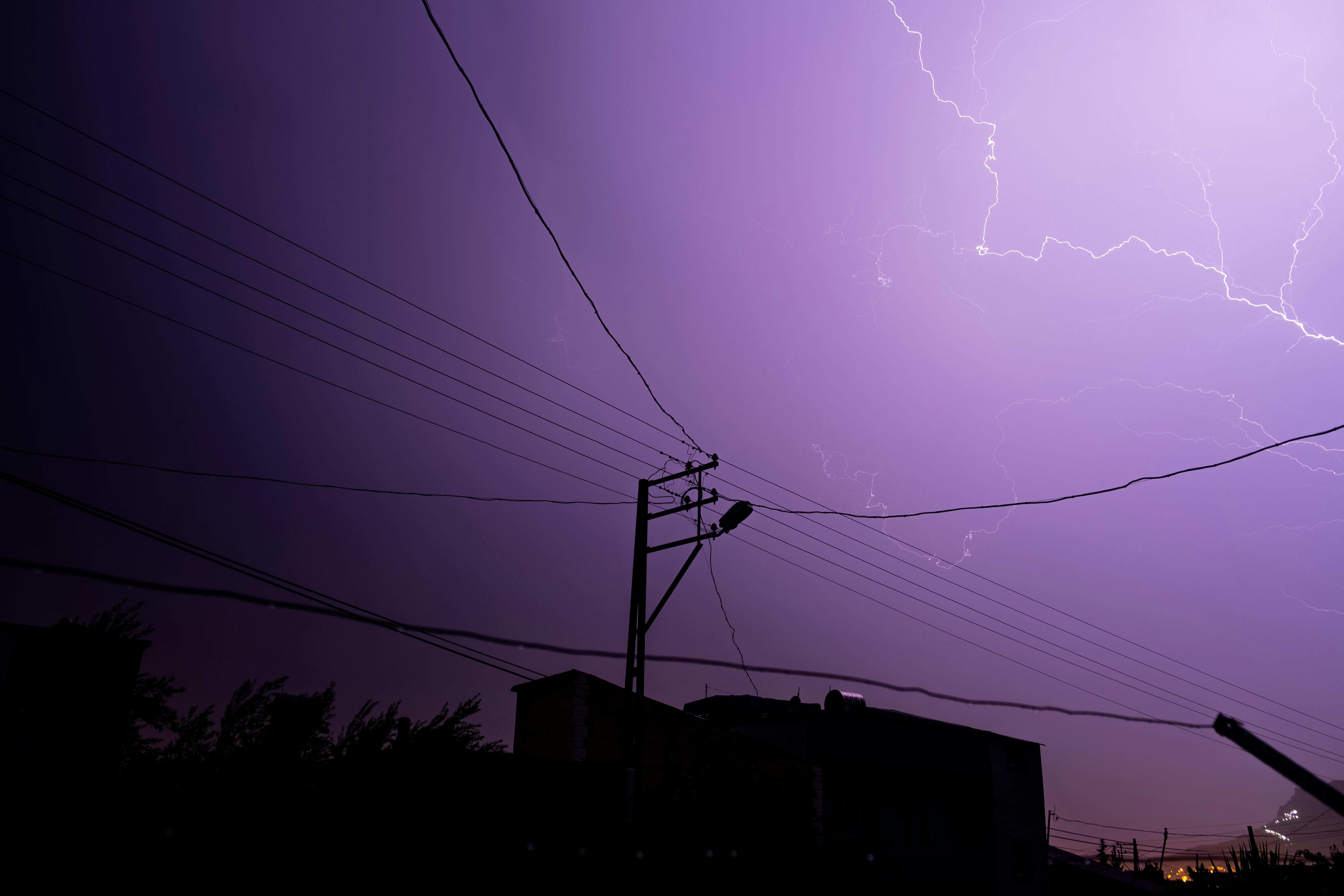 Captured in stunning clarity, a lightning storm illuminates the night sky above silhouetted urban structures.