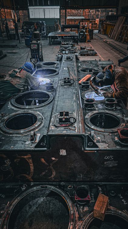 Industrial skilled-trades workers welding large metal structures