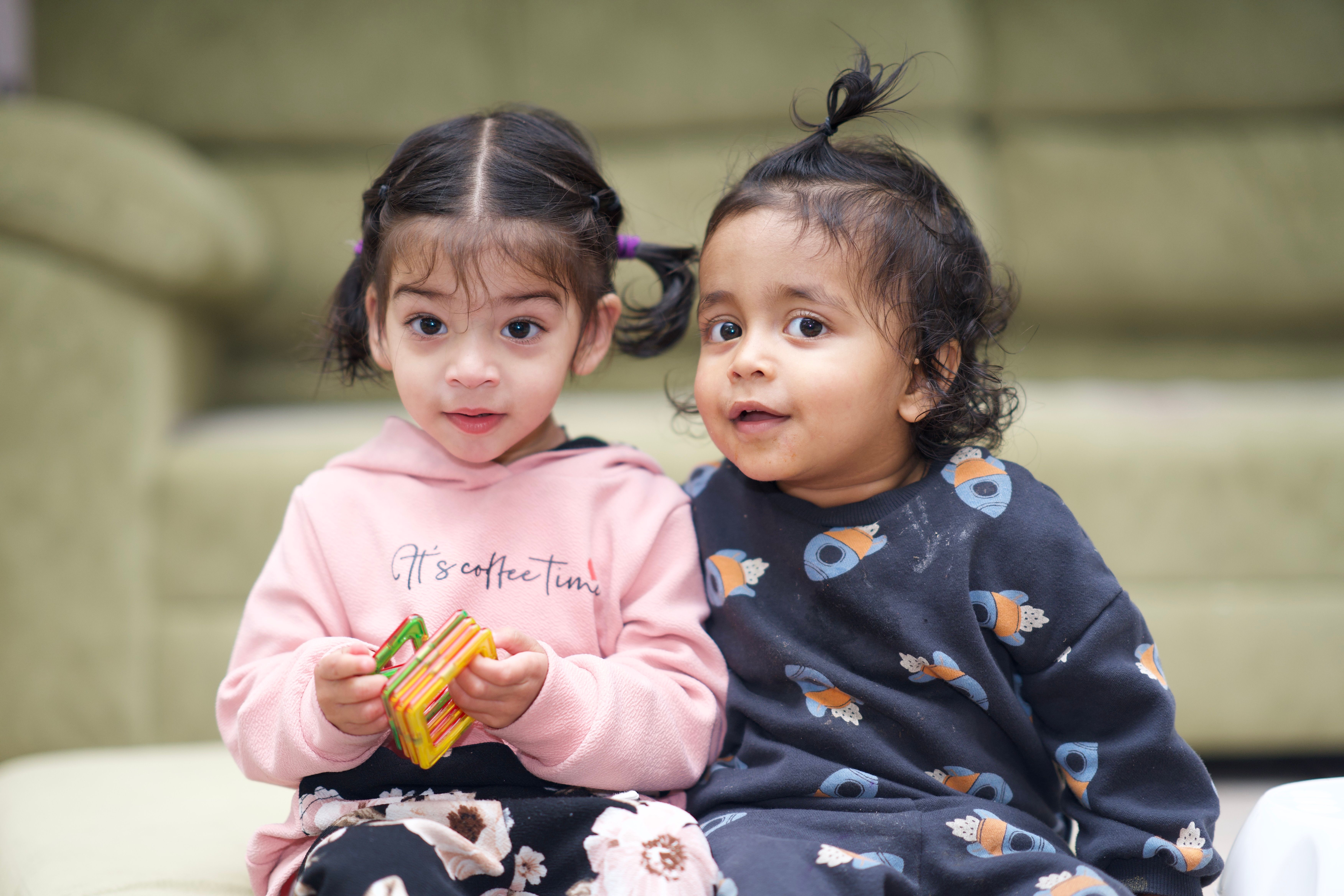 Cute kids enjoying playtime indoors with building blocks.