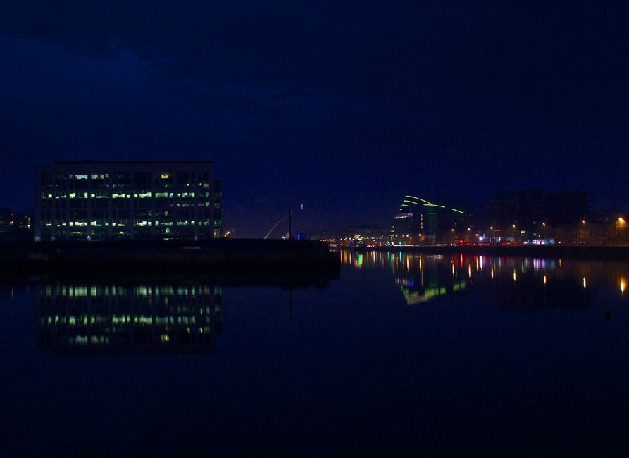 Stunning nighttime view of Dublin's skyline with building reflections in water.
