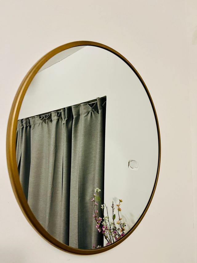 Round wall mirror with a warm brass rim — Teju on Pexels