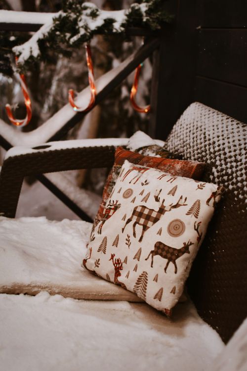 Free Snow-covered patio with festive cushion and holiday decor creates a warm winter scene. Stock Photo