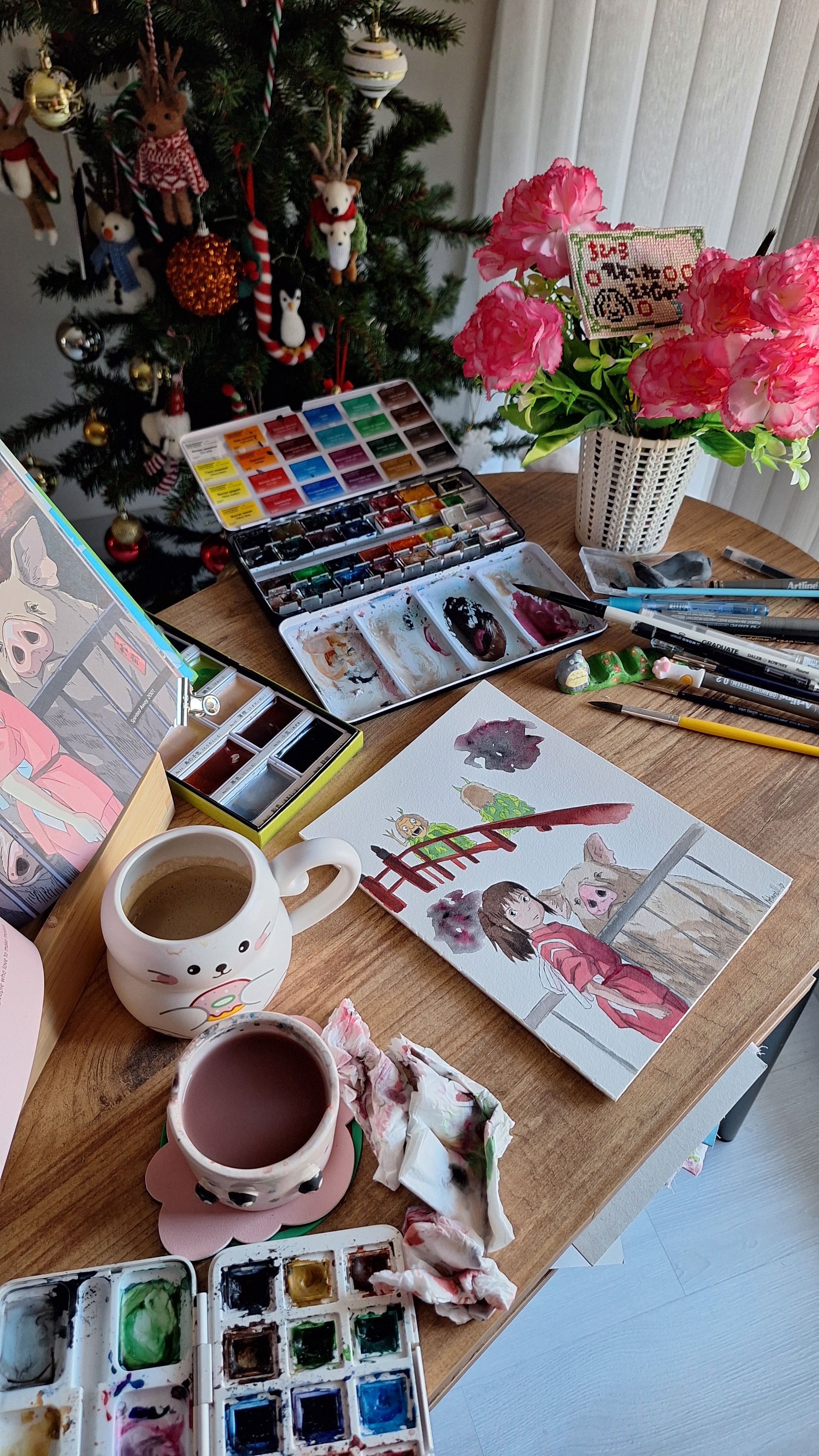A warm and cozy art studio scene with watercolors, paintings, and festive decorations.