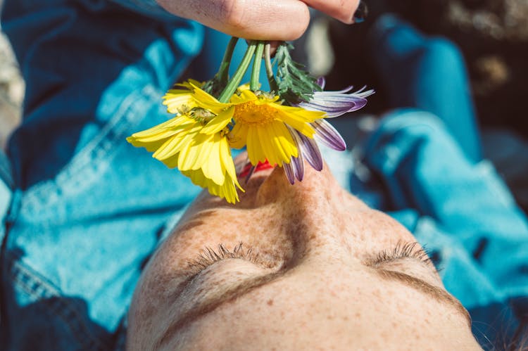 Close-Up Photo Of Person Smelling Flowers